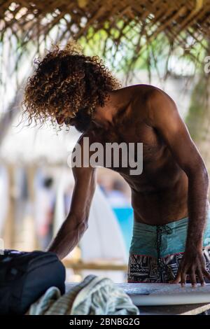 Surfer che ceretta la tavola da surf prima di pagaiare fuori a Hikkaduwa, Sri Lanka Foto Stock