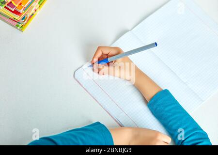 Scolastica facendo compiti, scrivendo, studiando lezione, scuola domestica del coronavirus Foto Stock