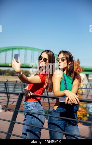 Sorridendo giovani migliori amici femminili che prendono selfie nel parco in una giornata estiva Foto Stock