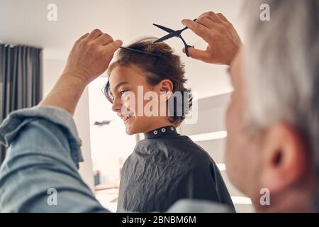 Cutie bambino sorridente mentre ottiene la nuova acconciatura Foto Stock