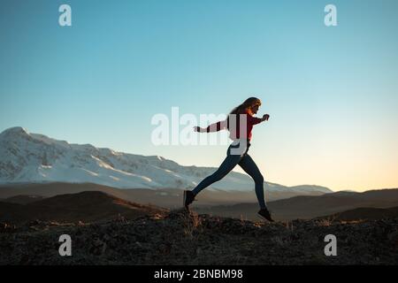 La ragazza snella e sportiva cammina in montagna al tramonto Foto Stock