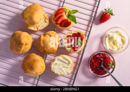 Gustosa colazione di focaccine con crema coagulata e marmellata di fragole su sfondo rosa, vista dall'alto Foto Stock