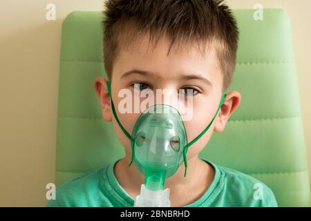 Bambino che fa l'inalazione con il nebulizzatore a casa. Concetto di attacco di asma Foto Stock