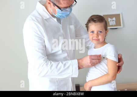 Il medico misura la temperatura di un bambino malato Foto Stock