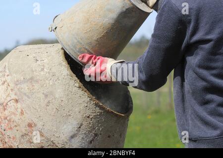 uomo lavorante costruttore che lavora con la parte anteriore del betoniera in cantiere Foto Stock