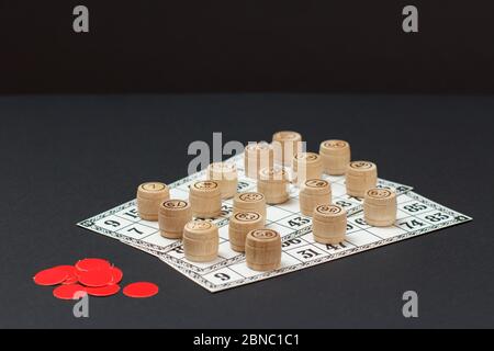 Lotto di gioco da tavolo. Botti di legno di lotto con carte di gioco e patatine rosse su sfondo nero. Foto Stock