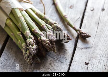 Asparagi verdi. Grappoli di asparagi verdi su sfondo grigio rustico in legno Foto Stock