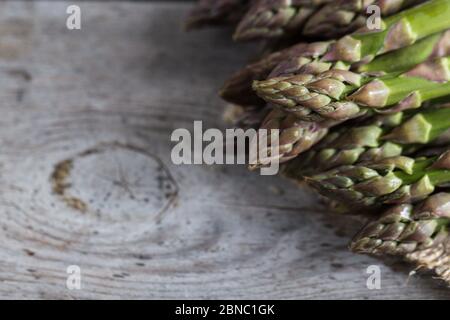 Asparagi verdi. Grappoli di asparagi verdi su sfondo grigio rustico in legno Foto Stock