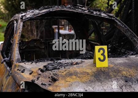 Dresda, Germania. 13 maggio 2020. Sul cofano di un'auto bruciata è presente una targa forense gialla del dipartimento investigativo criminale con il numero tre. Il veicolo distrutto è visibile sullo sfondo sfocato dell'immagine. Credit: Tino Plunert/dpa-Zentralbild/ZB/dpa/Alamy Live News Foto Stock