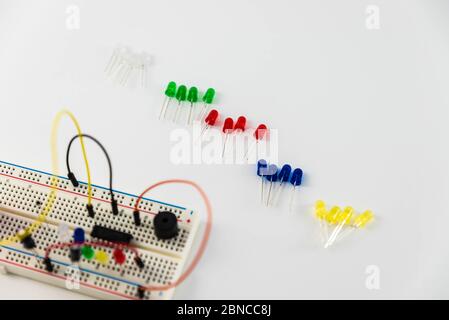 Microcontrollori, chip, resistori e diodi ad emissione luminosa su desktop bianco di un tecnico hardware. Progettare il luogo di lavoro Foto Stock