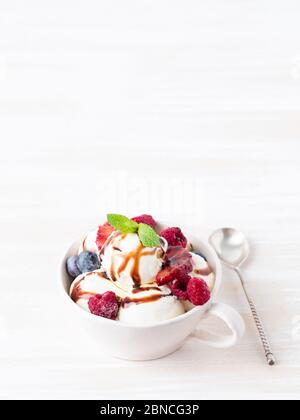 Palle di gelato alla vaniglia in tazza con lampone e mirtilli Foto Stock