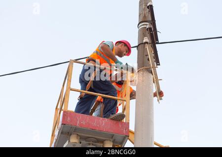 gli elettricisti sui montanti installano il supporto per la linea di alimentazione. Elettricisti professionisti lavorano sulla torre. Foto Stock