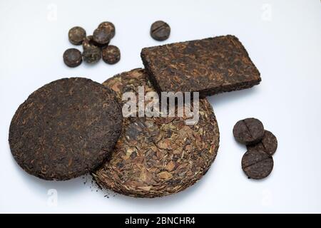 Frittelle pressate e mattoni di tè più puro di diversi tipi. Tè cinese secco di alta qualità. Tè bianco in frittella pressata su sfondo bianco. Gustoso Foto Stock