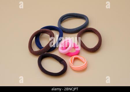 fasce elastiche per capelli di diversi colori su sfondo beige. Vista dall'alto di varie fasce elastiche. Cura dei capelli e accessori. Foto Stock