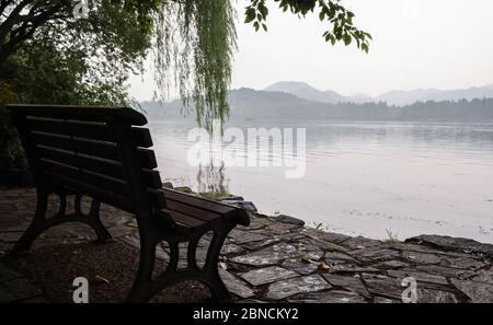 Vista dell'ambiente verde con alberi, panca e parco al lago Xihu o al lago occidentale al mattino, dove si trova un lago d'acqua dolce a Hangzhou, Zhejian Foto Stock