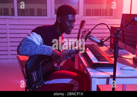 Crea musica e un concetto di studio di registrazione - un chitarrista africano americano che registra una traccia di chitarra elettrica in studio domestico Foto Stock