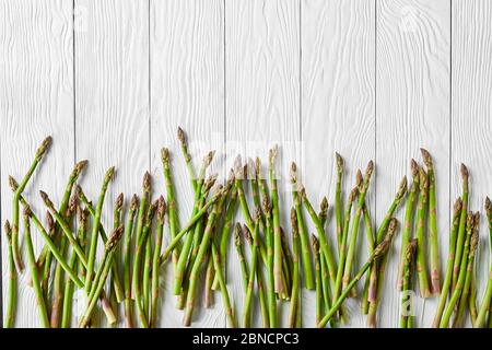 asparagi verdi freschi su un tavolo di legno bianco, piatto, spazio libero Foto Stock