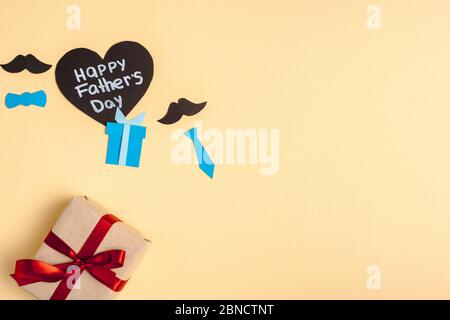 vista dall'alto della scatola regalo, elementi decorativi in carta e biglietto a forma di cuore con scritta happy pads day su sfondo beige Foto Stock