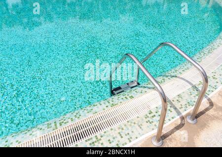 Ringhiere in acciaio inox per una piscina con acqua pulita, limpida e blu. Foto Stock
