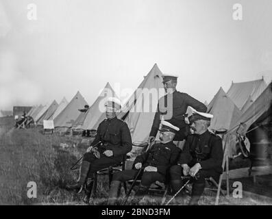 Fotografie d'epoca tardo vittoriana, scattate nel 1903, che mostrano i membri del 2° London Fuces, o la 2° City of London Rifle Volontarier Corps. Non è sicuro che queste fotografie siano state scattate in Inghilterra o in Sud Africa, dove molti volontari erano basati in questo momento. Foto mostra un gruppo di quattro ufficiali seduti e in piedi neonati di una linea di tende di tela. Foto Stock