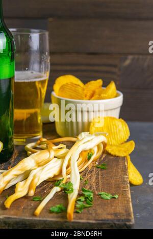 Formaggio con birra, limone e patatine su tavola di legno scuro. Snack sul pesce con birra. Viste frontali, primo piano Foto Stock