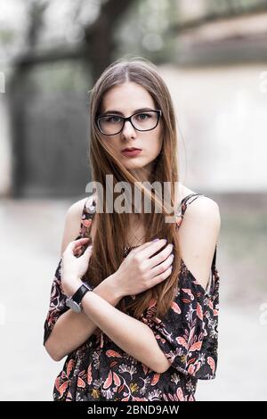 giovane millenario dai capelli bruni con occhiali e abito leggero Foto Stock