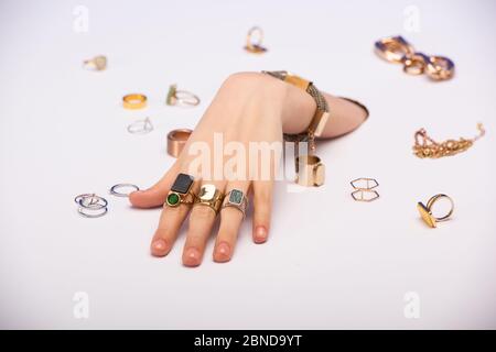 vista tagliata di donna con bracciale a mano vicino anelli dorati su bianco Foto Stock