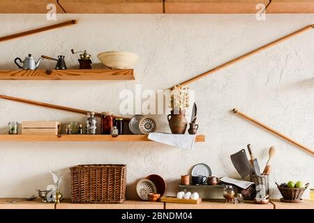 tazze e ciotole di argilla sugli scaffali vicino alle uova grezze di noccioline e frutta gustosa in cucina Foto Stock