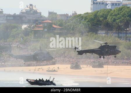 Serie 36 di 165 gommoni AAV-7A veicoli anfibi sulla spiaggia e Eurocopter AS332B1 Super Puma e Sikorsky SH-3 Sea King Armed Forces Day Foto Stock