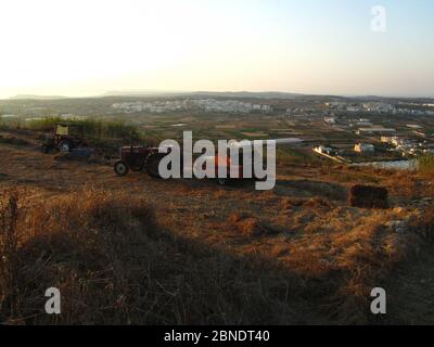 MGARR, MALTA - 19 luglio 2014: Un trattore o una mietitrice, veicolo agricolo, parcheggiato in un campo, dopo aver tagliato il grano e accatastarlo per il fieno. Agricoltura Foto Stock