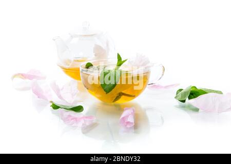 tè estivo con fiori di petali di rosa in una tazza di vetro Foto Stock