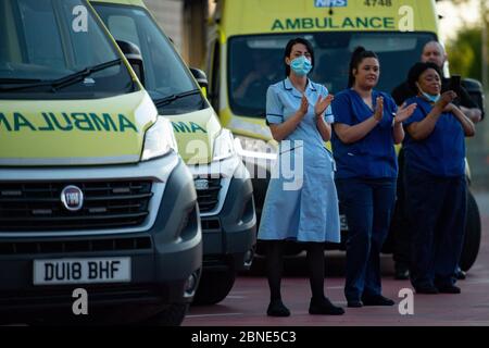 Il personale dell'NHS fuori dal Queen Elizabeth Hospital di Birmingham, mentre si uniscono agli applausi per salutare gli eroi locali durante il Clap for Carers di giovedì per riconoscere e sostenere i lavoratori e gli assistenti dell'NHS che combattono la pandemia del coronavirus. Foto Stock