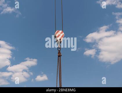 Il gancio della gru con strisce rosse e bianche pensili, cielo blu in background. Foto Stock