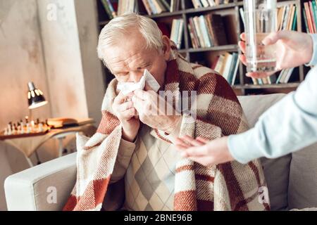 Padre e figlia in casa biblioteca donna che dà acqua e medicine Foto Stock