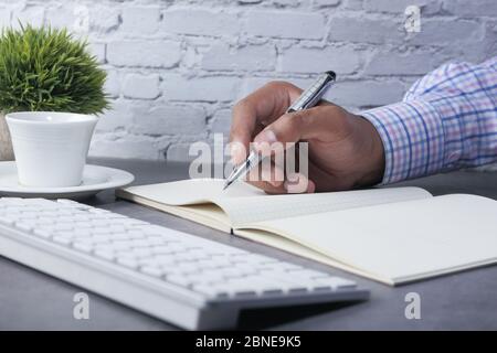 Primo piano della persona che scrive a mano su blocco note. Foto Stock