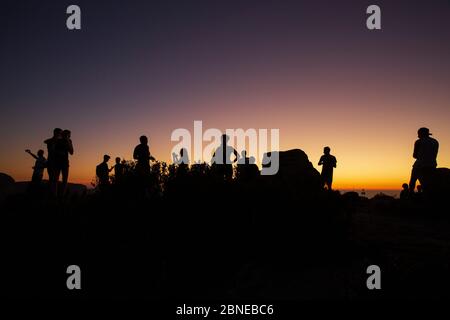 silhouette di persone che guardano il tramonto dalla cima della testa dei leoni, città del capo, sud africa Foto Stock