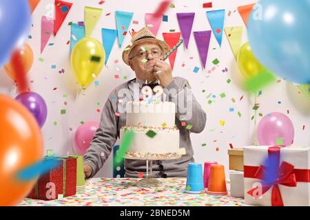 Anziano festeggia il compleanno con una torta, palloncini e confetti Foto Stock