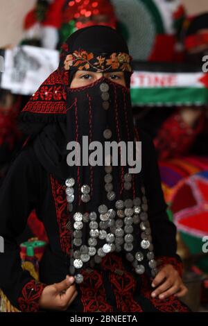 Khan Younis, Gaza. 14 maggio 2020.il rifugiato palestinese Abir Amarna, di tredici anni, siede con i suoi familiari in abiti tradizionali, in commemorazione del 66° anniversario della 'Nakbaa', araba per 'catastrofe', termine usato per segnare gli eventi che hanno portato alla fondazione di Israele nel 1948, a Khan Yunis, Nella parte meridionale della striscia di Gaza, mercoledì 14 maggio 2020. Essi celebrano il 72° anniversario di 'Nakbaa' (giorno della catastrofe), mentre a casa a causa della pandemia del coronavirus COVID-19. Credit: UPI/Alamy Live News Foto Stock