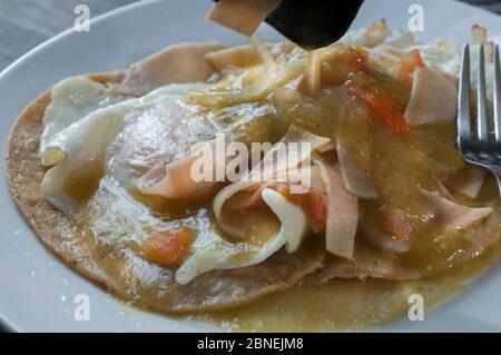 Salsa verde speziata in cima ai rancheros huevos, fotografia da vicino o macro, concetto di colazione messicana Foto Stock