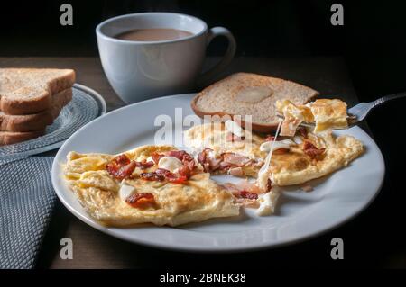 Prosciutto di pancetta e frittata di formaggio con pane tostato e caffè sul lato in fondo nero, cibo del mattino o concetto di colazione Foto Stock