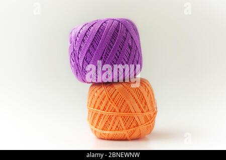 Due matasse di filo in viola e arancione. Lavorazione a maglia su sfondo bianco. Hobby. Foto Stock