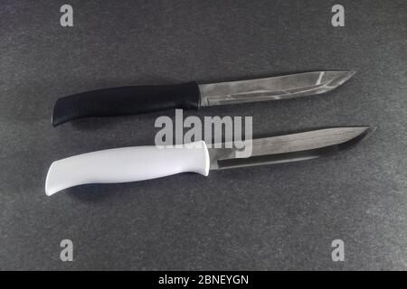Due coltelli da cucina con manici bianchi e neri su sfondo scuro da vicino. Foto Stock