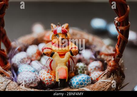 Primo piano di un giocattolo da coniglietto e caramelle pasquali a forma di uovo in un cestino Foto Stock