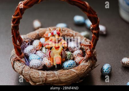 Primo piano di un giocattolo da coniglietto e caramelle pasquali a forma di uovo in un cestino Foto Stock