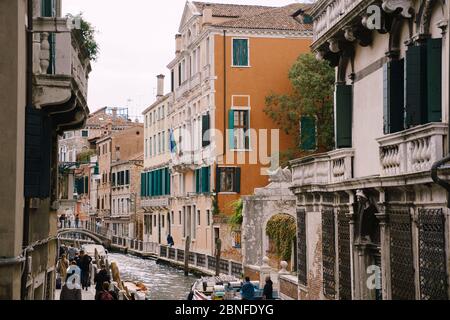 Vista classica dello stretto canale veneziano. Edifici colorati si ergono di fronte l'uno all'altro, barche ormeggiate vicino alla riva, gondoliere cavalcare i turisti su un Foto Stock