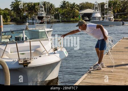 Un uomo tenta di attraccare la sua barca da drifting ad un molo al Sandsprit Park a Port Salerno, Florida, USA. Foto Stock