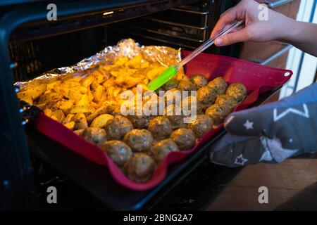 Closeup di polpette appena sfornate e zeppe di patate Foto Stock
