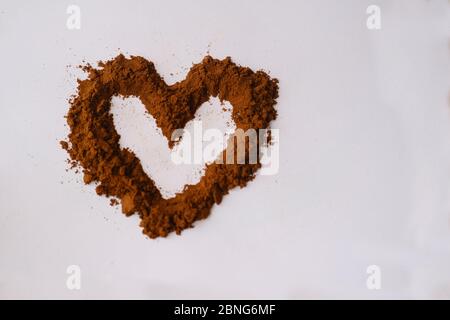 Forma a cuore creata con caffè su sfondo bianco Foto Stock