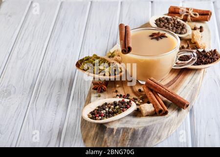 Bevanda indiana tradizionale - tè masala con spezie. Cannella, cardamomo, anice, zucchero, chiodi di garofano, pepe su uno sfondo di legno chiaro Foto Stock