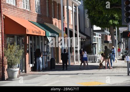 Beverly Hills, CA/USA - 7 maggio 2020: Una linea di clienti socialmente si distanziano in attesa di entrare in uno Starbucks durante la quarantena del coronavirus Foto Stock